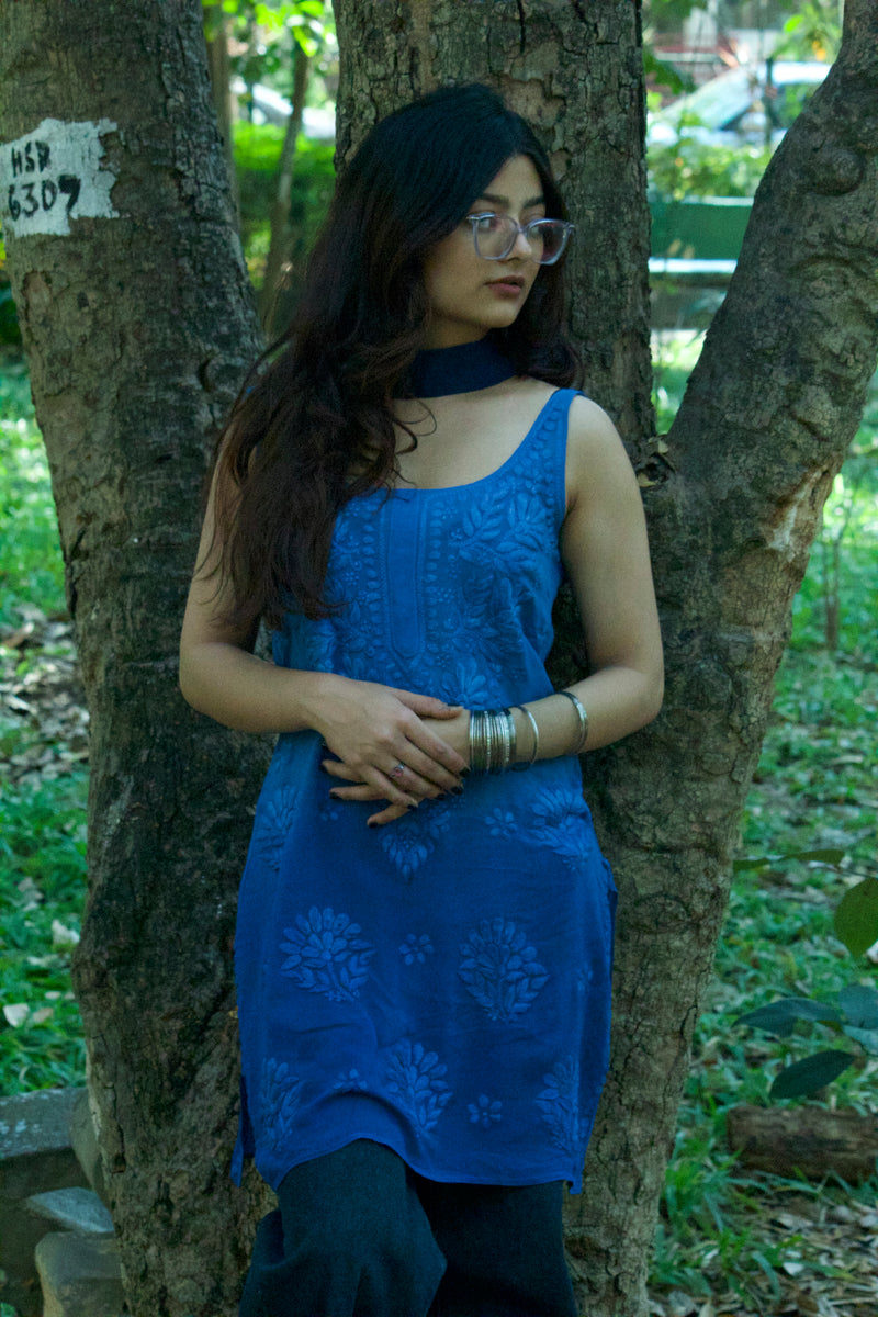 Model is standing wearing a handcradfted blue chikankari kurti with corset back and the slim dupatta/scarf