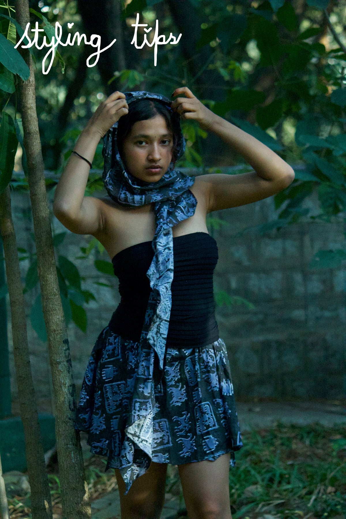 Woman adjusting a scarf in a forest setting